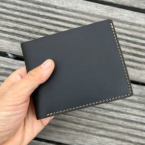 Carteira masculina de couro preto com costura marrom, design elegante e minimalista.