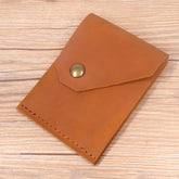 Porta-cartões de couro marrom com botão, ideal para organizar documentos.
