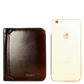 Carteira de couro marrom da marca Manbang ao lado de um smartphone dourado.