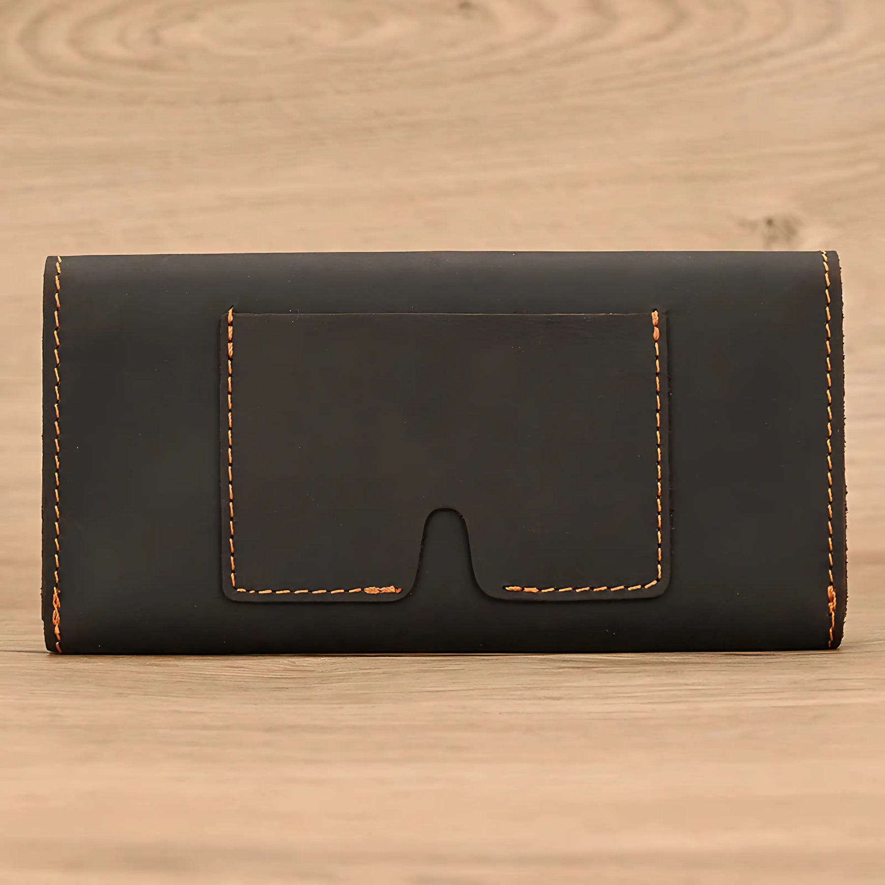 Porta-cartões em couro preto com costura em tom laranja, elegante e discreto.