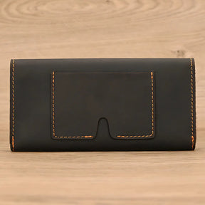 Porta-cartões em couro preto com costura em tom laranja, elegante e discreto.