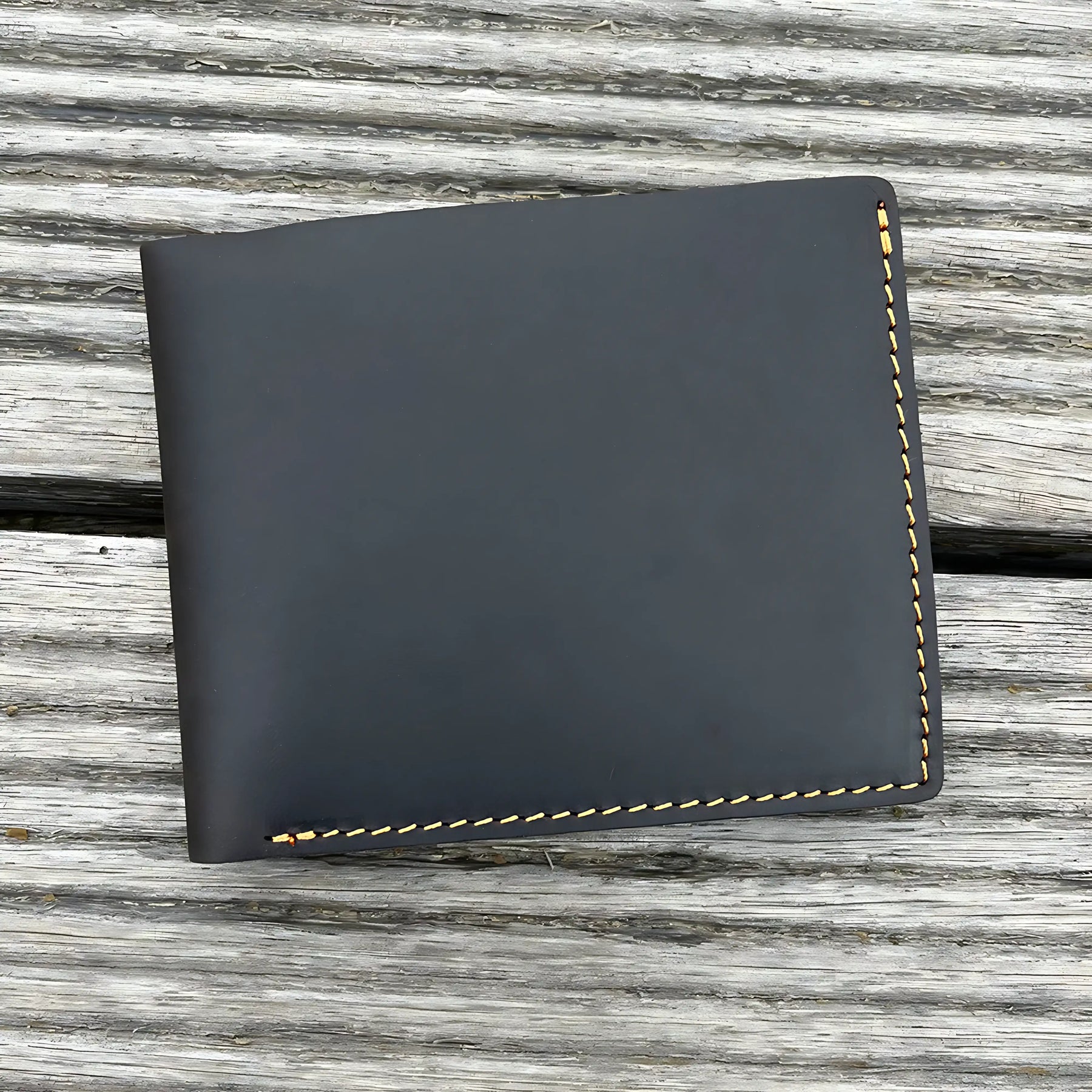 Carteira de couro preto com costura amarela, elegante e compacta.