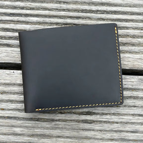Carteira de couro preto com costura amarela, elegante e compacta.