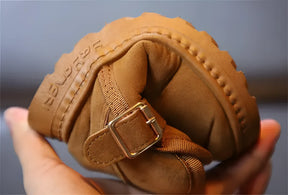 bota infantil forrada com fecho na cor marrom demonstrando a qualidade do material sendo dobrado e não rachar.