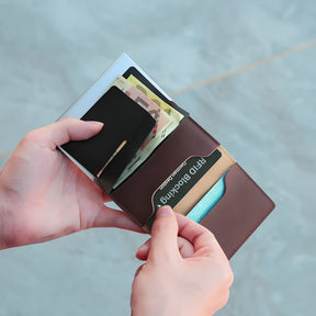 Uma pessoa inserindo seu cartão em um compartimento interno da carteira masculina slim.