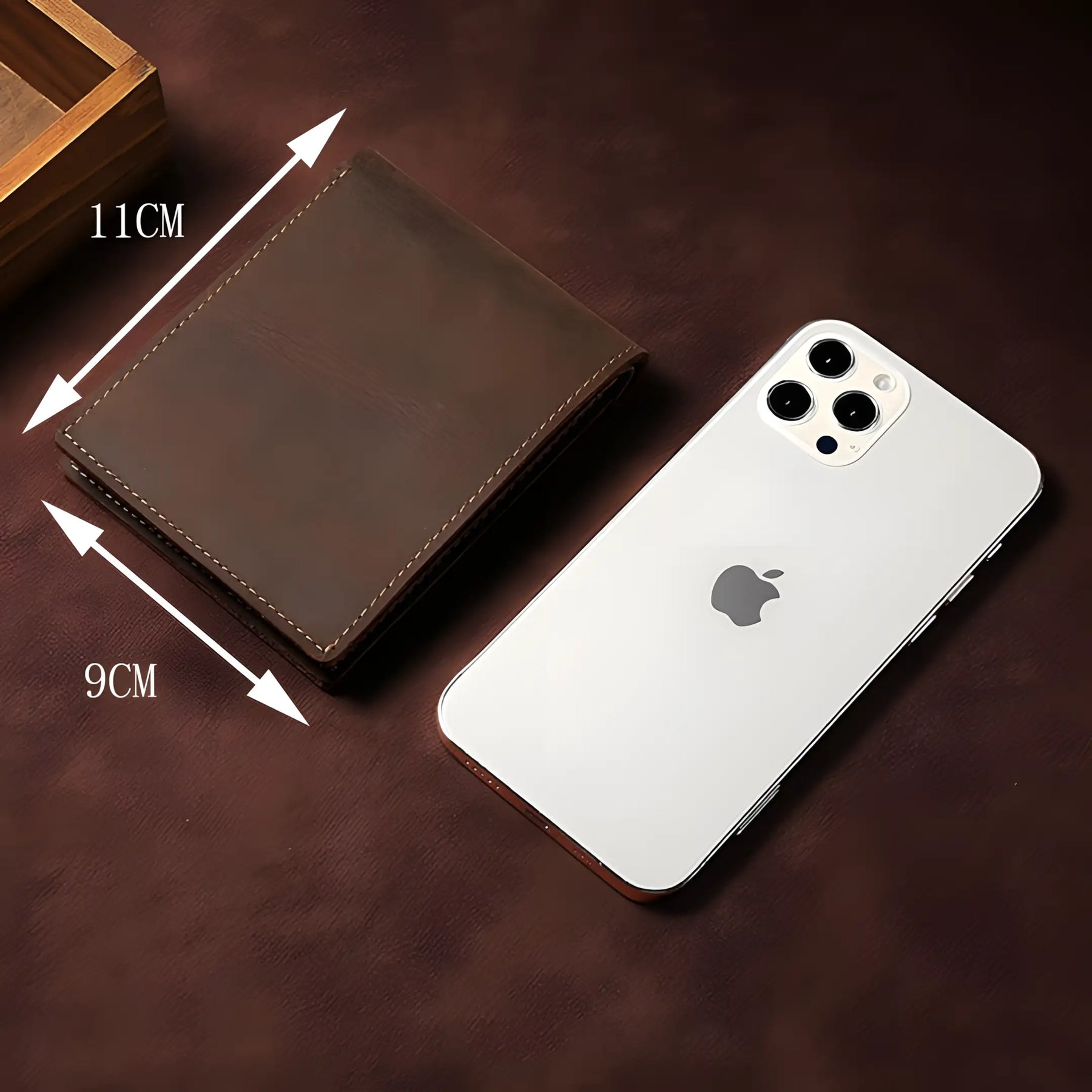 carteira masculina slim em couro modelo horizontal sendo exibida fechada ao lado de um iphone para demonstrar suas dimensões.