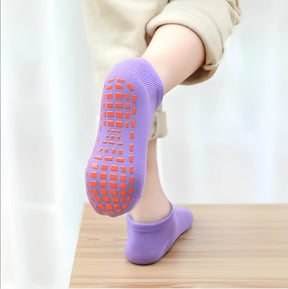 meia infantil antiderrapante na cor roxo claro sendo usada por uma criança, realçando o solado em borracha.