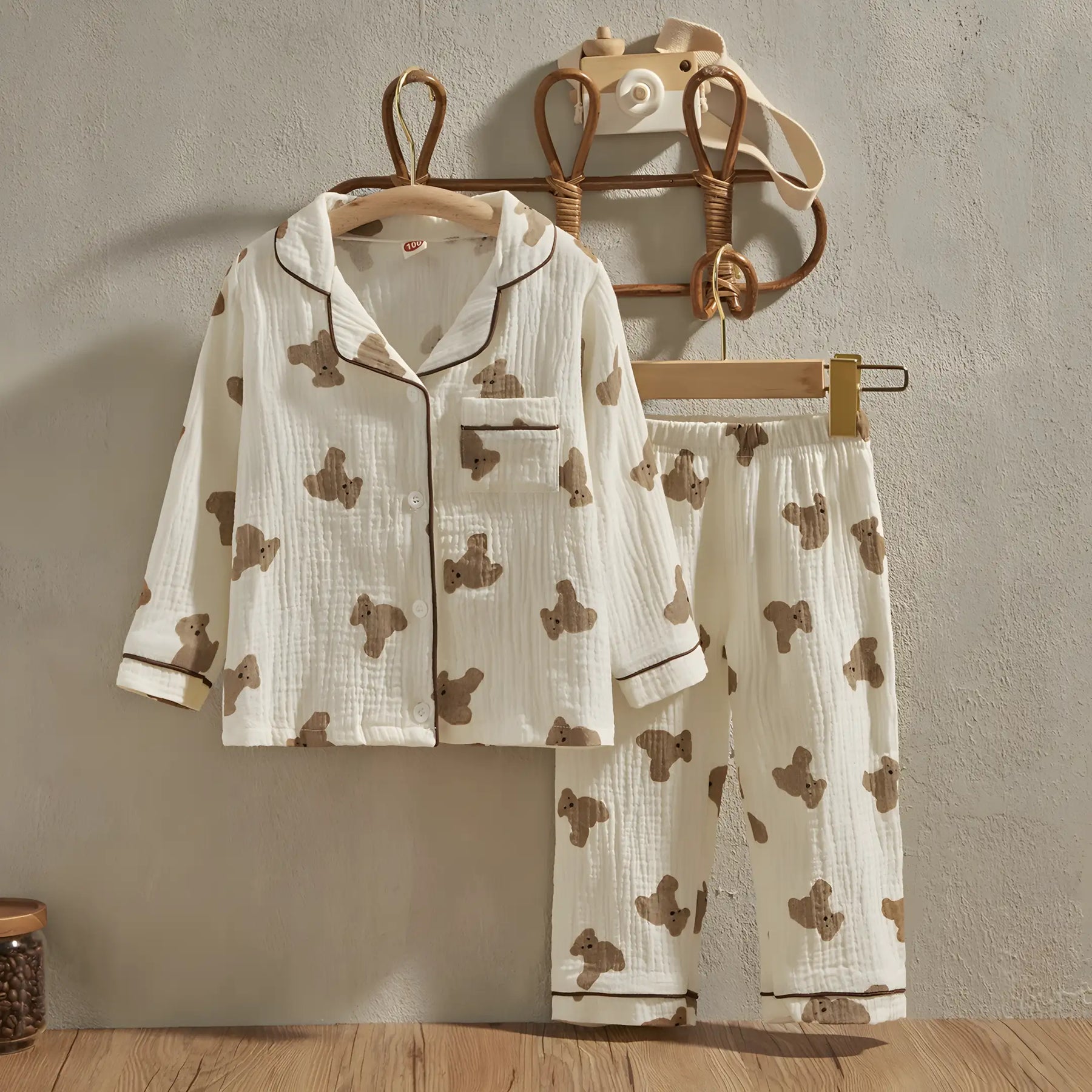 pijama infantil casual exibindo a parte frontal pendurado em cabide encostados na parede.